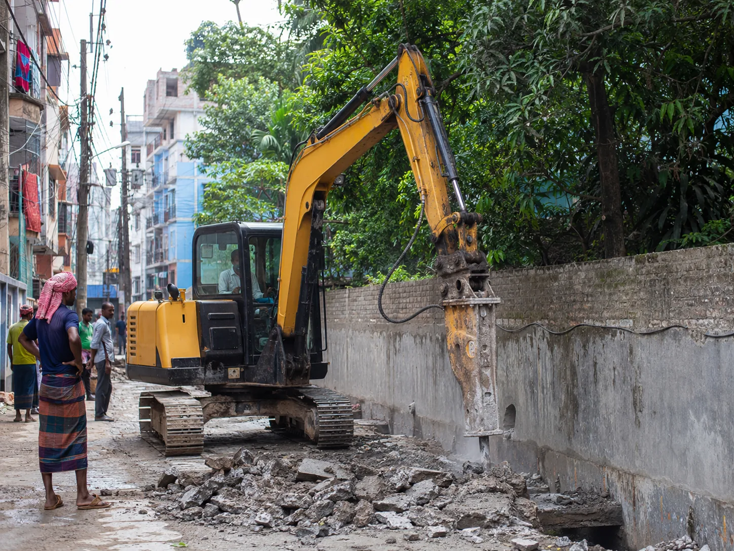 ১২ টন হ্যামার এক্সকাভেটর শহুরে গলি ও boundary wall-এর পাশে breaking work করছে